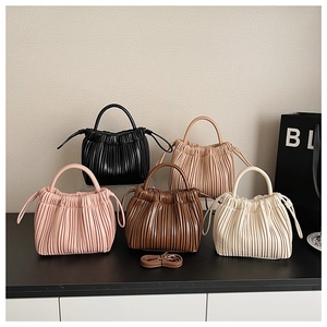 Detailed view of pleated bucket bags in five colors with round handles and straps