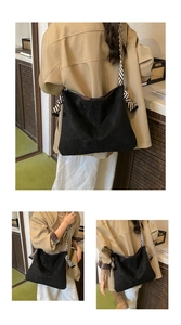 Detail of a black suede tote bag with a black and white twill wide shoulder strap and knots