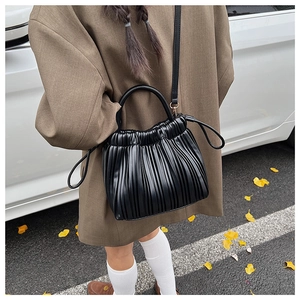 Detail of black pleated cloud bucket bag with round top handle and drawstring element