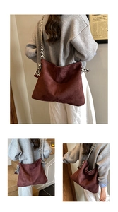 Detail of brown suede tote bag featuring a black and white striped woven wide shoulder strap