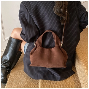 Detail of dark brown suede dumpling bag with elegant pleats and slim leather strap