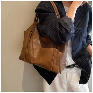 Vue détaillée du sac cabas en cuir caramel avec franges latérales et texture souple
