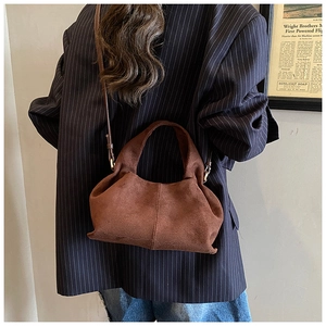 Close-up of brown suede bucket bag featuring elegant pleats and minimalist cloud silhouette
