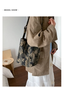 Model view of a large camouflage canvas tote bag worn as a crossbody bucket shoulder bag