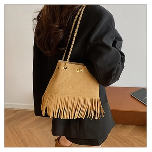 Detail of khaki suede bucket bag with fringe and gold chain strap on model