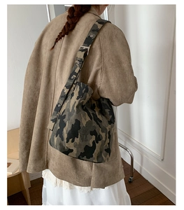 Close-up of camouflage canvas shoulder bag with adjustable metal eyelet strap detail