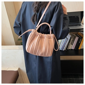 Detail of light pink pleated bucket bag with soft leather texture and stylish shoulder strap