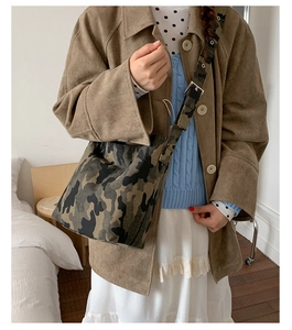 Detail of adjustable wide canvas strap and camo pattern on oversized bucket bag