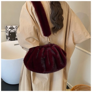 Detail of burgundy faux mink fur cloud bag featuring soft pleated texture and gold buckles