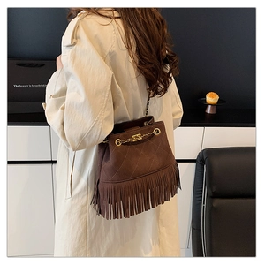 Close-up of brown suede bucket bag with quilted patterns and long fringe details