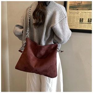Detail of burgundy matte tote bag with decorative black and white striped shoulder strap