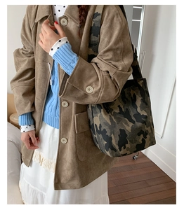 Detail view of the camouflage canvas tote bag with wide strap on a model shoulder