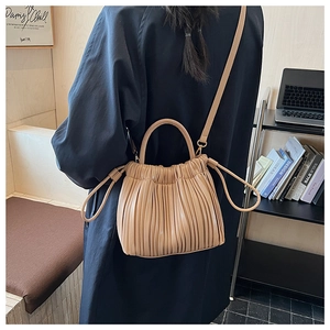Detailed view of beige pleated bucket bag with drawstring closure and crossbody strap