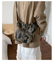 Detailed view of camouflage canvas tote bag with wide strap on model back