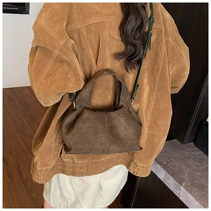 Detail of vintage brown suede bucket bag with stylish fold design and adjustable strap