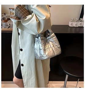 Detailed side view of silver quilted puffer tote bag showing padded texture and metallic finish