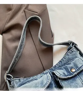 Close-up of vintage blue denim bag featuring a wide strap and decorative metal button