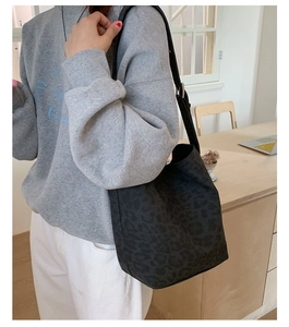 Detail of black leopard print hobo bag with adjustable strap in casual indoor setting