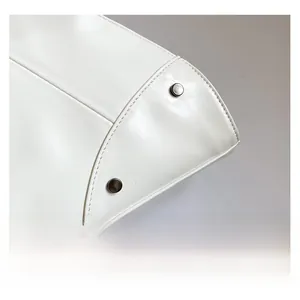 Macro view of white leather tote bag featuring meticulous stitching and vintage metal rivets
