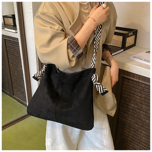 Detail of black matte suede tote bag featuring black and white striped rope shoulder strap