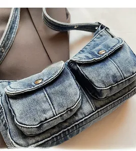 Detailed close-up of washed blue denim bag with multi-pocket design and metal buttons