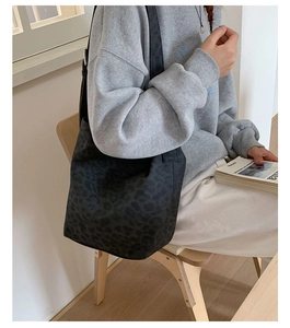 Detailed view of the dark leopard print shoulder bag with its textured fabric and wide strap