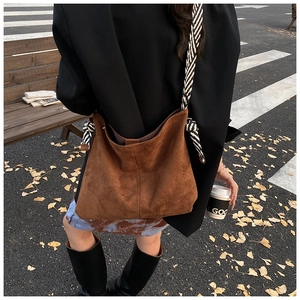 Close-up of brown suede tote bag featuring a thick black and white striped rope strap