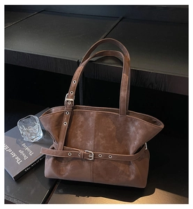 Detail of dark brown suede tote bag with adjustable straps and decorative buckle