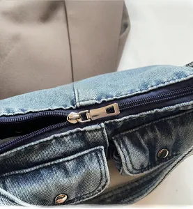 Close-up of smooth silver metal zipper and rivet details on blue denim motorcycle bag