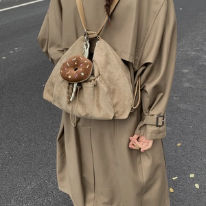 Detalle de la mochila de ante caqui con un lindo colgante de peluche de dónut de chocolate