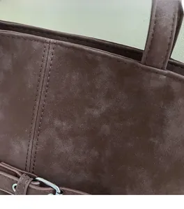 Detail of premium brown suede tote bag with durable double stitching and metal hardware