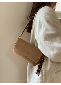 Close-up of brown suede rectangular crossbody bag with wooden bead tassel and long strap