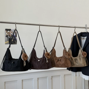 Detalle de elegantes bolsos de hombro en cuatro colores con acabado de ante y dijes