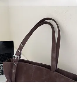 Detailed view of dark brown tote bag with adjustable shoulder strap and silver buckle