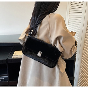 Detail of black faux fur shoulder bag with silver square lock on beige trench coat