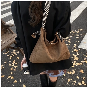 Detail of dark brown suede Hobo bag with striped silk scarf strap in autumn outdoor setting