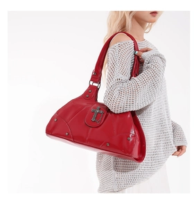 Detail view of red punk style punk shoulder bag with vintage cross charm and metal studs