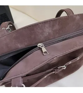 Detail of silver zipper hardware and suede texture on dark brown tote bag