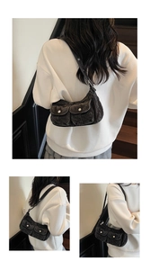 Close-up of vintage grey denim armpit bag featuring utility pockets and metallic snaps