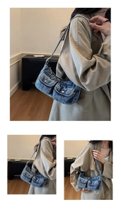 Detail of vintage blue denim underarm bag with double front utility pockets and silver hardware