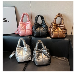 Detail of quilted metallic space cotton handbags in five shiny colors on a black leather sofa