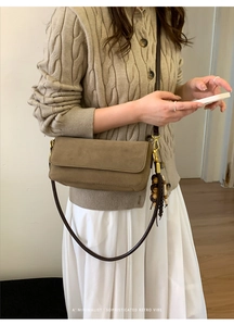 Retro brown suede crossbody bag with decorative wooden beads on a cable-knit sweater