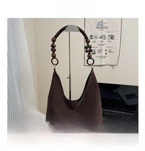 Détail d'un sac hobo marron foncé rétro avec poignée en perles de bois et texture mate