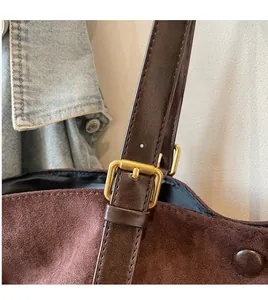Detail of dark brown suede tote with leather strap and golden square adjustment buckle