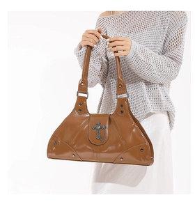 Close-up of brown oil wax leather tote featuring silver cross pendant and rivet details