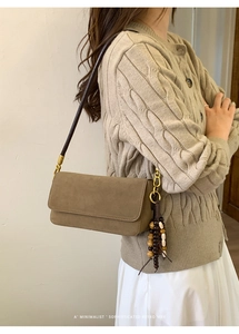 Detail of dark coffee suede shoulder bag with minimalist flap and beaded tassel accent