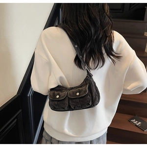 Close-up of retro washed black denim shoulder bag with dual flap pockets and silver buttons