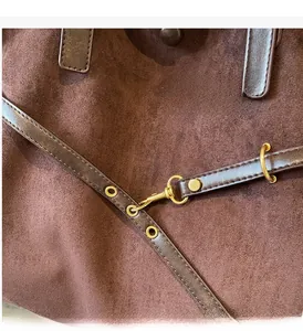 Detail of dark brown suede tote featuring vintage brass hardware and reinforced stitching