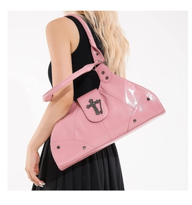 Detail of pink punk style shoulder bag with metallic cross and silver studs on a model