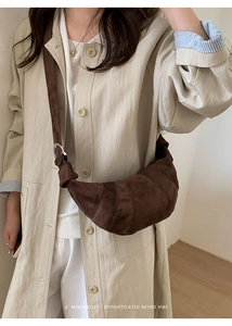 Detail of dark brown suede croissant bag worn with minimalist beige coat styling